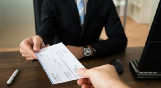 Empresario entregando la liquidación en forma de cheque a un trabajador al que ha despedido.